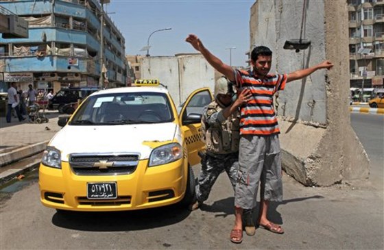 An Iraqi man raises his hands as an Iraqi police officer conducts a body search at a check point in central Baghdad on Saturday.